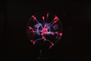 Crystal glass plasma ball with glowing electric lights inside placed in dark room